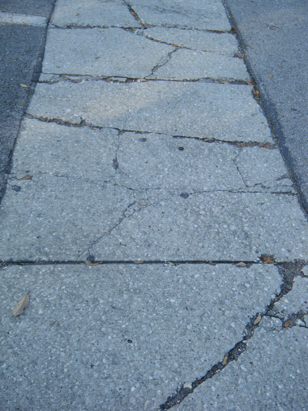 Cracked concrete sidewalk with visible damage.
