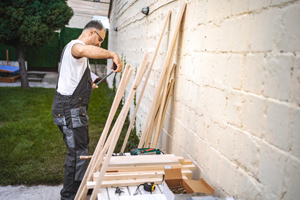 Carpenter measuring wood planks outdoors
